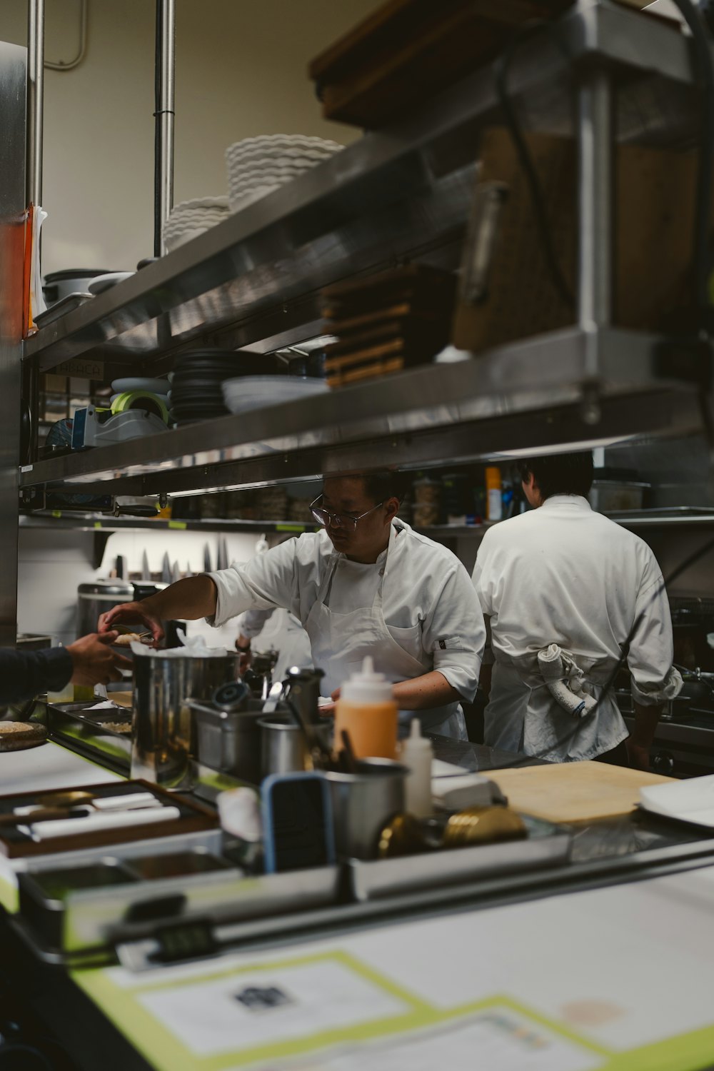 Chefs in whites working along the stainless-steel line of a busy professional kitchen